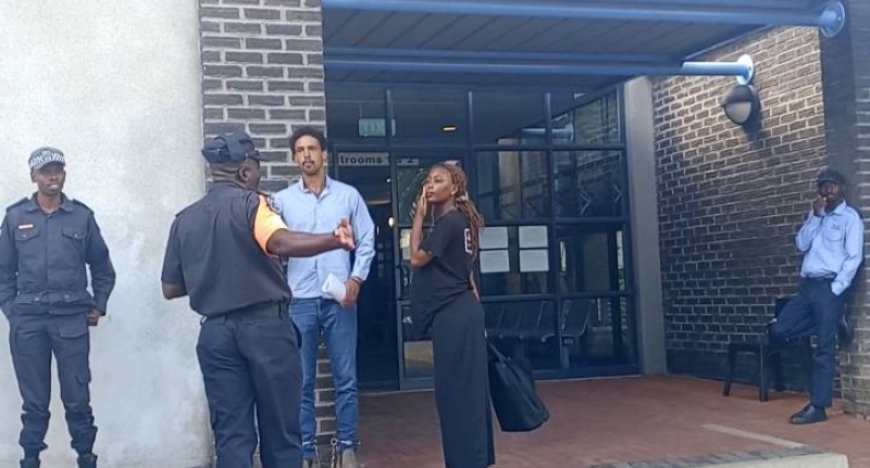 Holland (in sky blue shirt and shackles) talking to police officers
