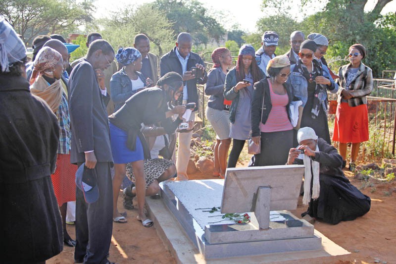 Segametsi Mogomotsi's family and friends taking pictures of her tombstone after the unveiling ceremony .