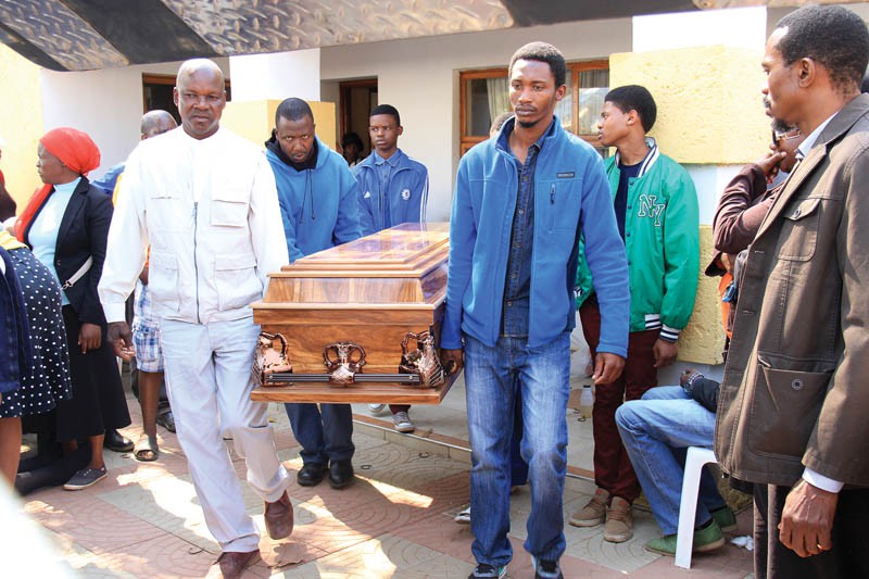 The sons taking away the casket back to the morgue, after momentarily blocking the funeral