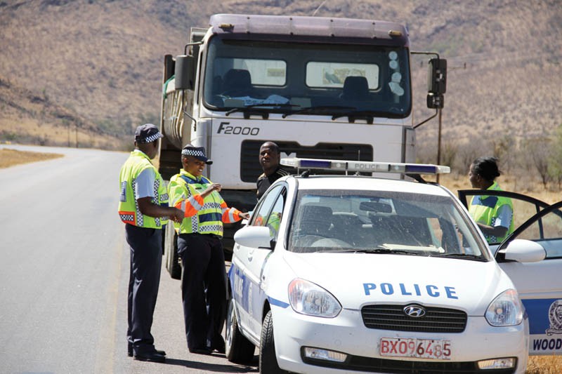 Police officers confronting a truck driver. Vehicles whose drivers fail to pay police fines are flagged without notification of owners. Three bus operators want the regulation scrapped.